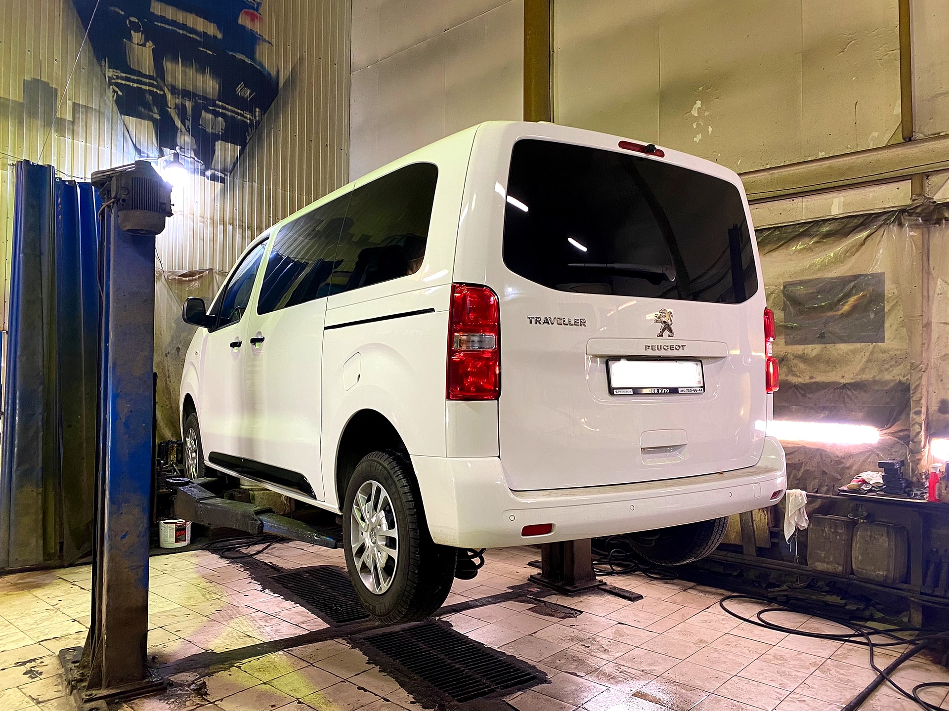 Белый Peugeot Traveller на двухстоечном подъёмнике в цехе - РБ Групп