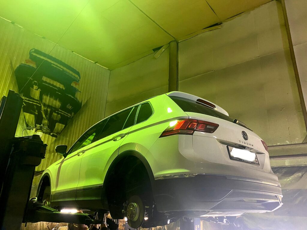 Белый Volkswagen Tiguan на двухстоечном подъёмнике, заднее колесо снято - цех РБ Групп